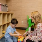 Speech therapist working on the floor with a child using colorful shapes