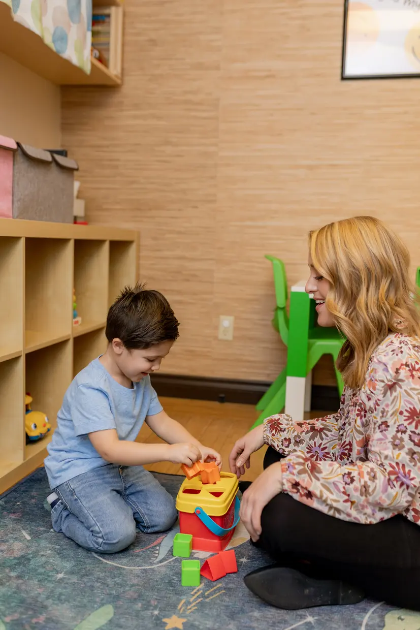 Speech therapist working on the floor with a child using colorful shapes at Ocean Beach Speech