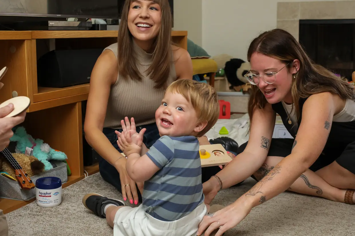 Speech therapist engaging a toddler in communication through play on the floor