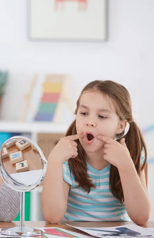 Child practicing speech sounds with a mirror during a therapy session